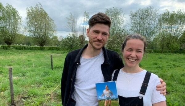 Man en vrouw in weiland met boek in handen