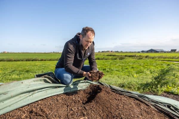 Man op een mesthoop houdt aarde in zijn handen